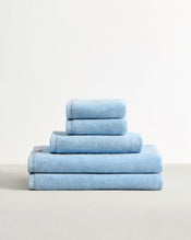 A neatly folded stack of Bed Threads Sky 100% Cotton Terry Bath Sheet Bundle is arranged on a light surface against a plain white background, showcasing bath sheets and towels in various sizes. - view