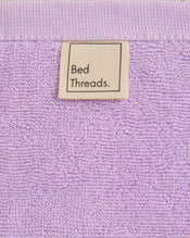 A close-up of Violet 100% Cotton Terry Face Washers (Set of Two) by Bed Threads, featuring a fabric label sewn near the edge—absorbent, gentle on the skin, and perfect for daily cleansing. - view
